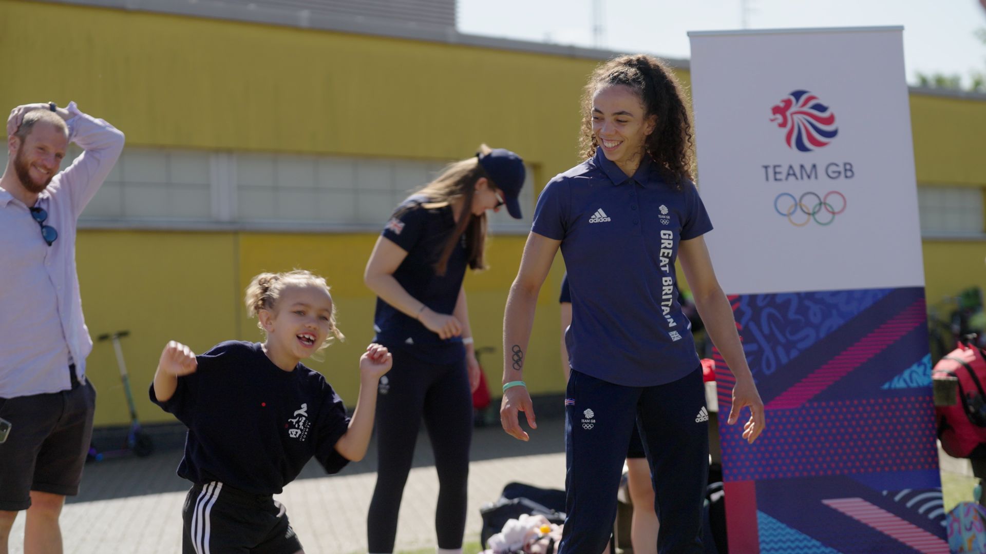 Team GB athlete engaging with a young child who is smiling and laughing