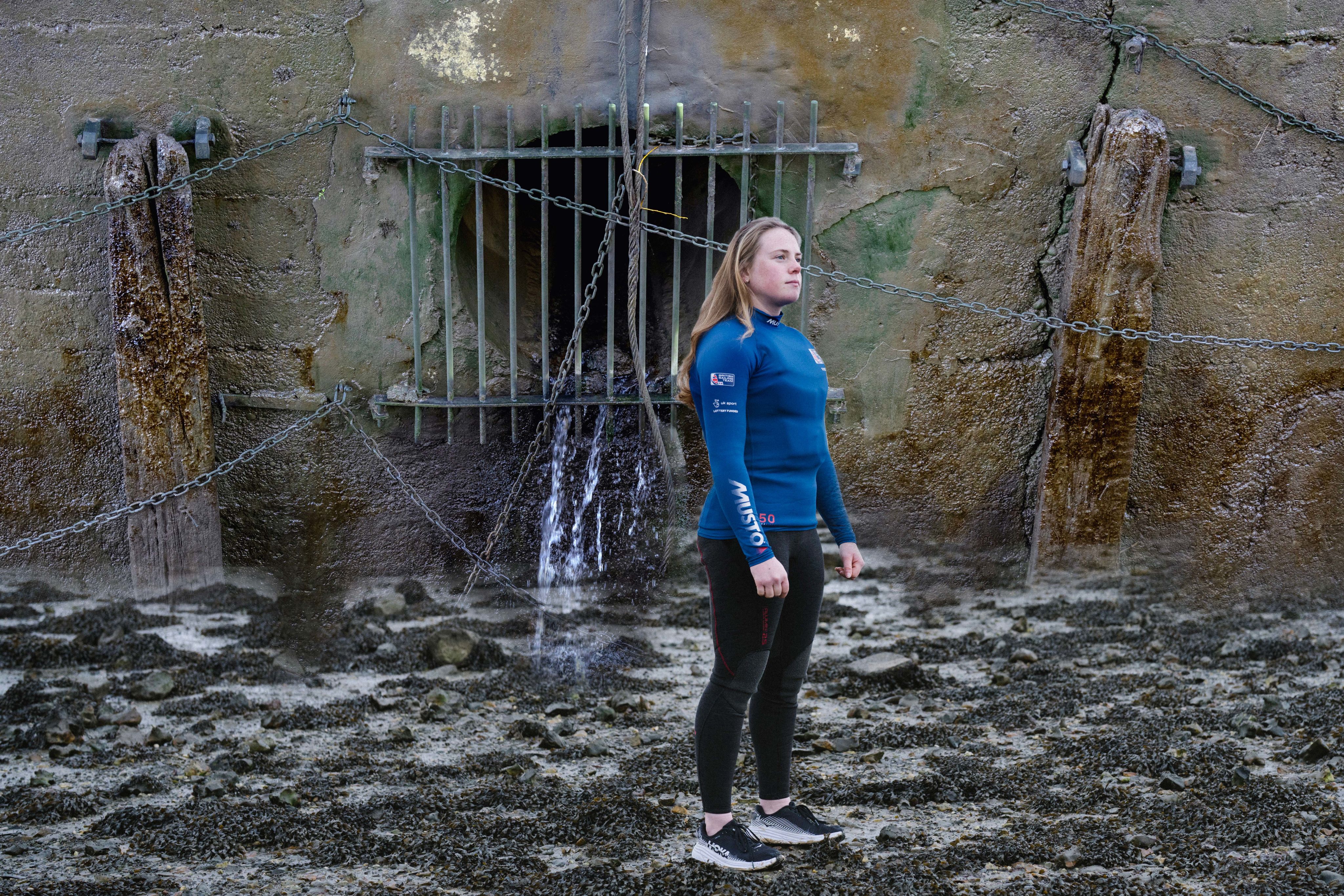 Young female sailor stands on shore infront of sewer