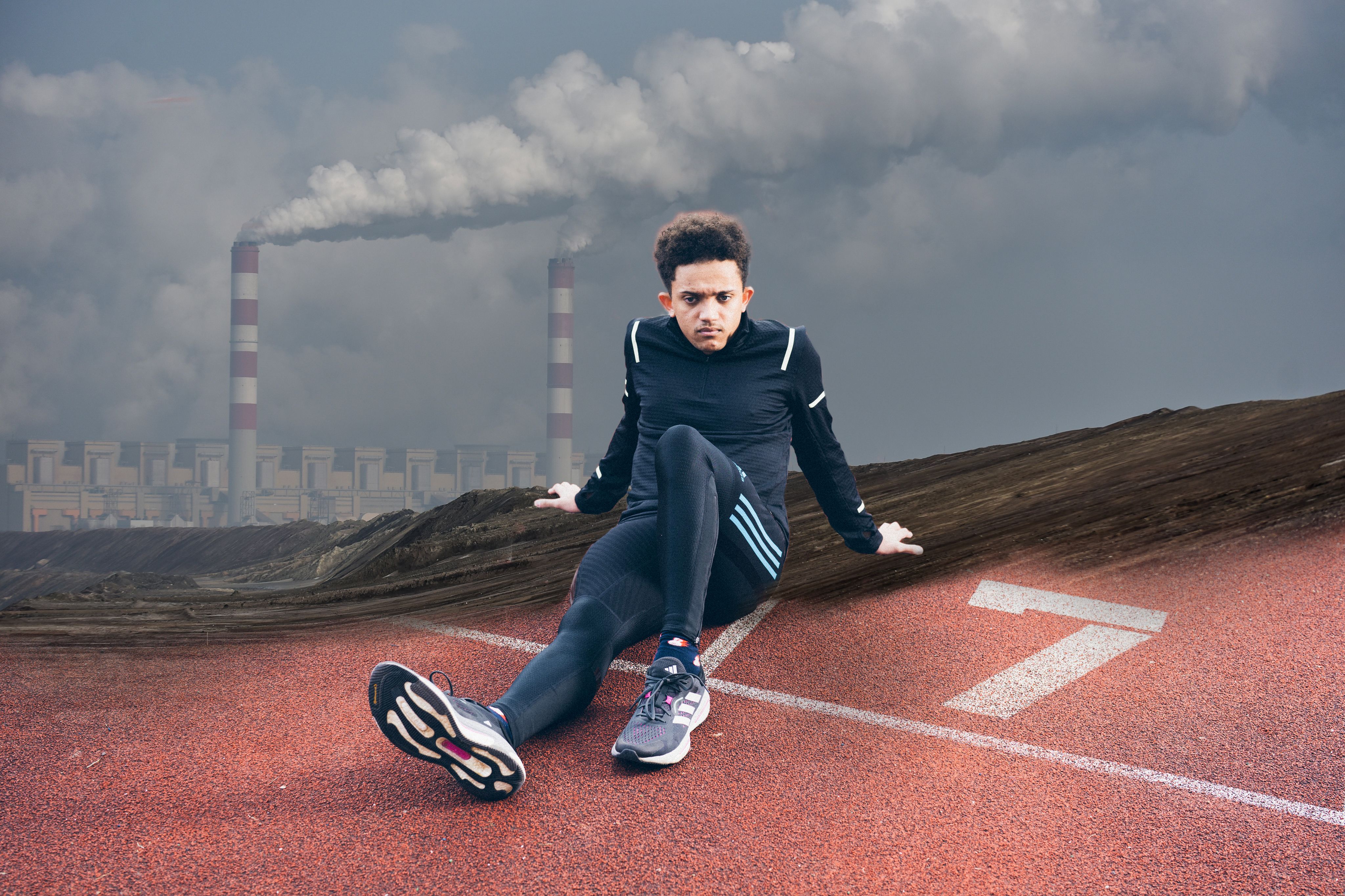 Sprinter sitting on track against a backdrop of pollution