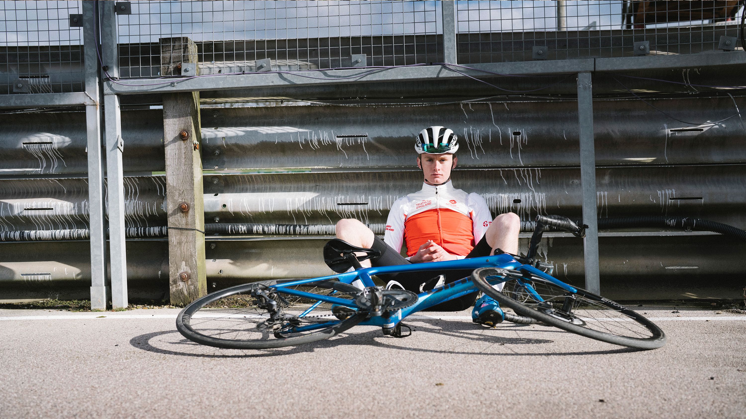 Young cyclist sits against rail