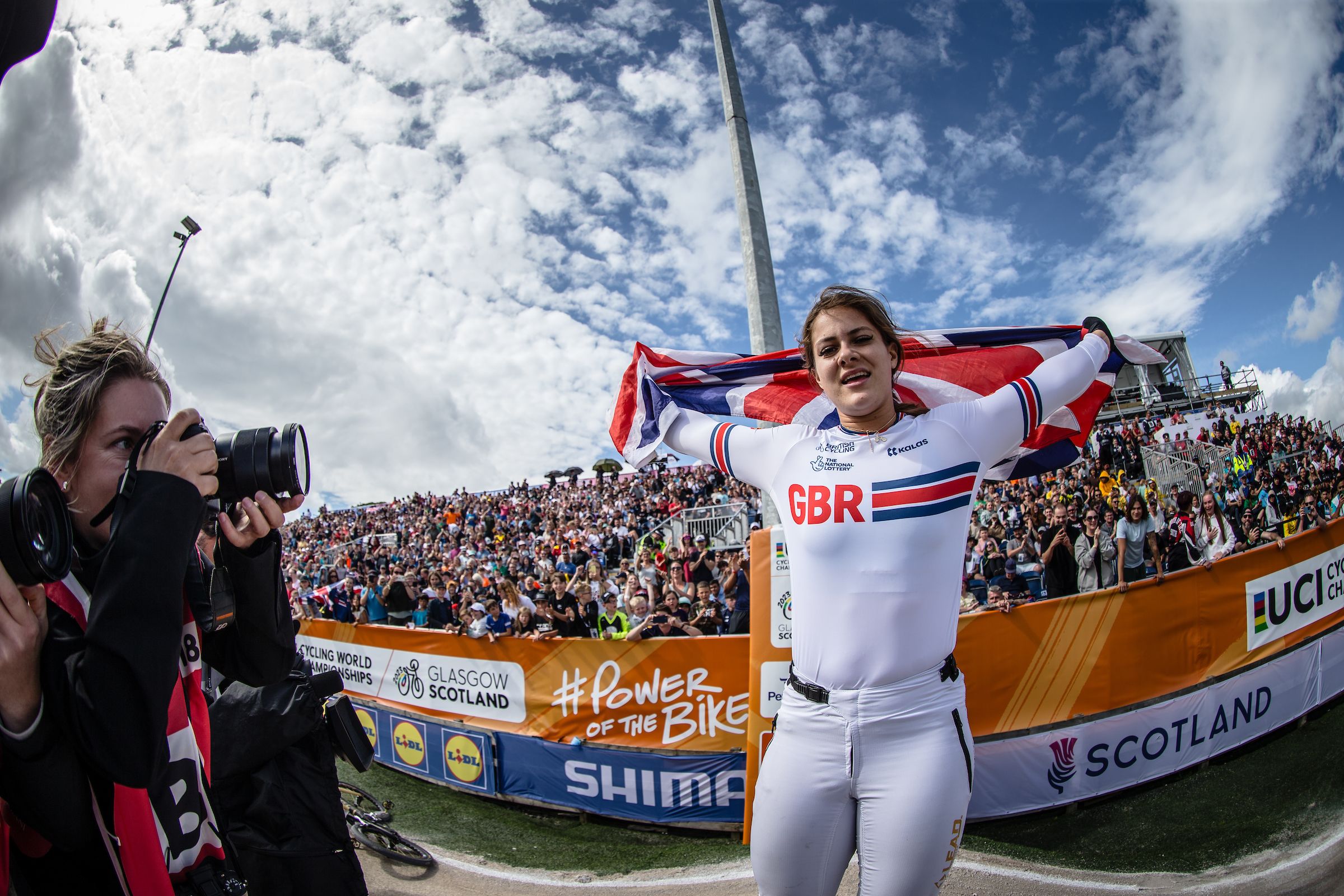 Beth Shriever waves a Union Jack flag after winning the women's elite BMX World Championship title in Glasgow at the 2023 UCI Cycling World Championships