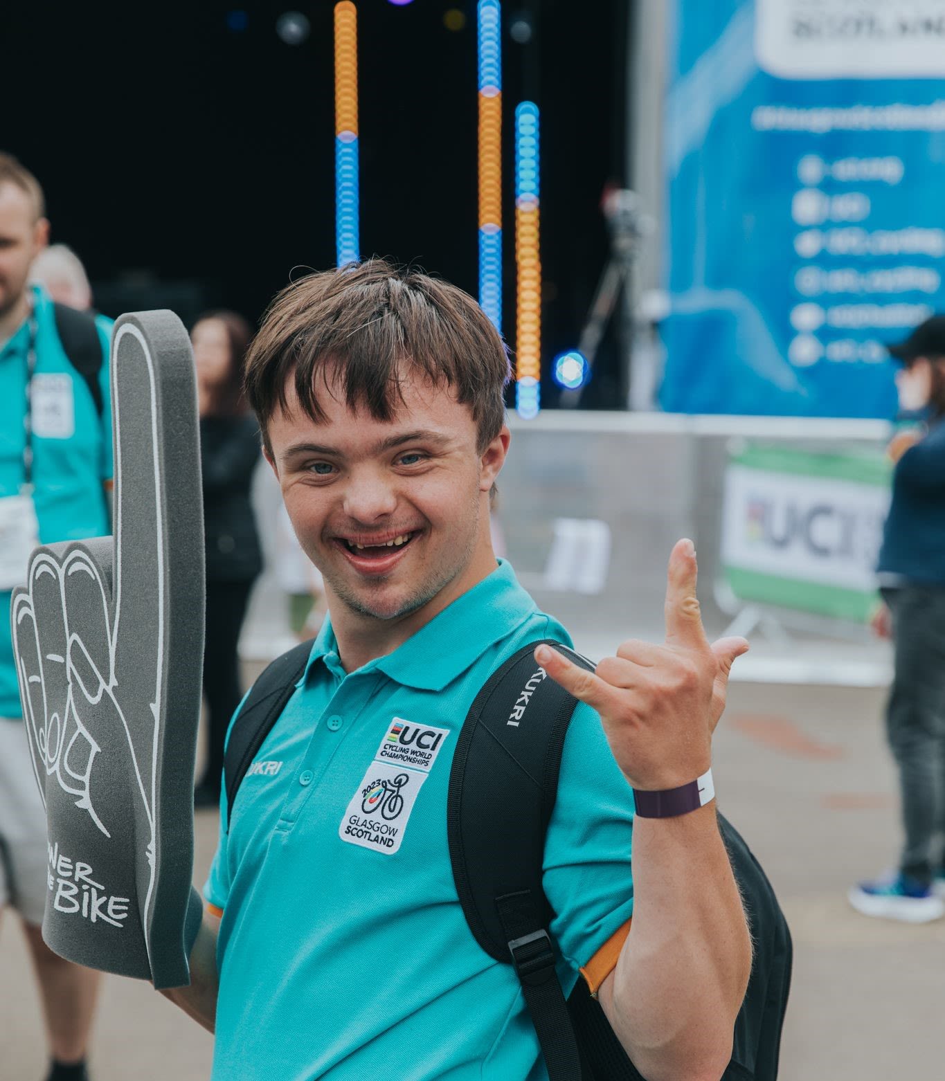 a volunteer pictured at the 2023 UCI Cycling World Championships giving a rock-on hand gesture to the camera.