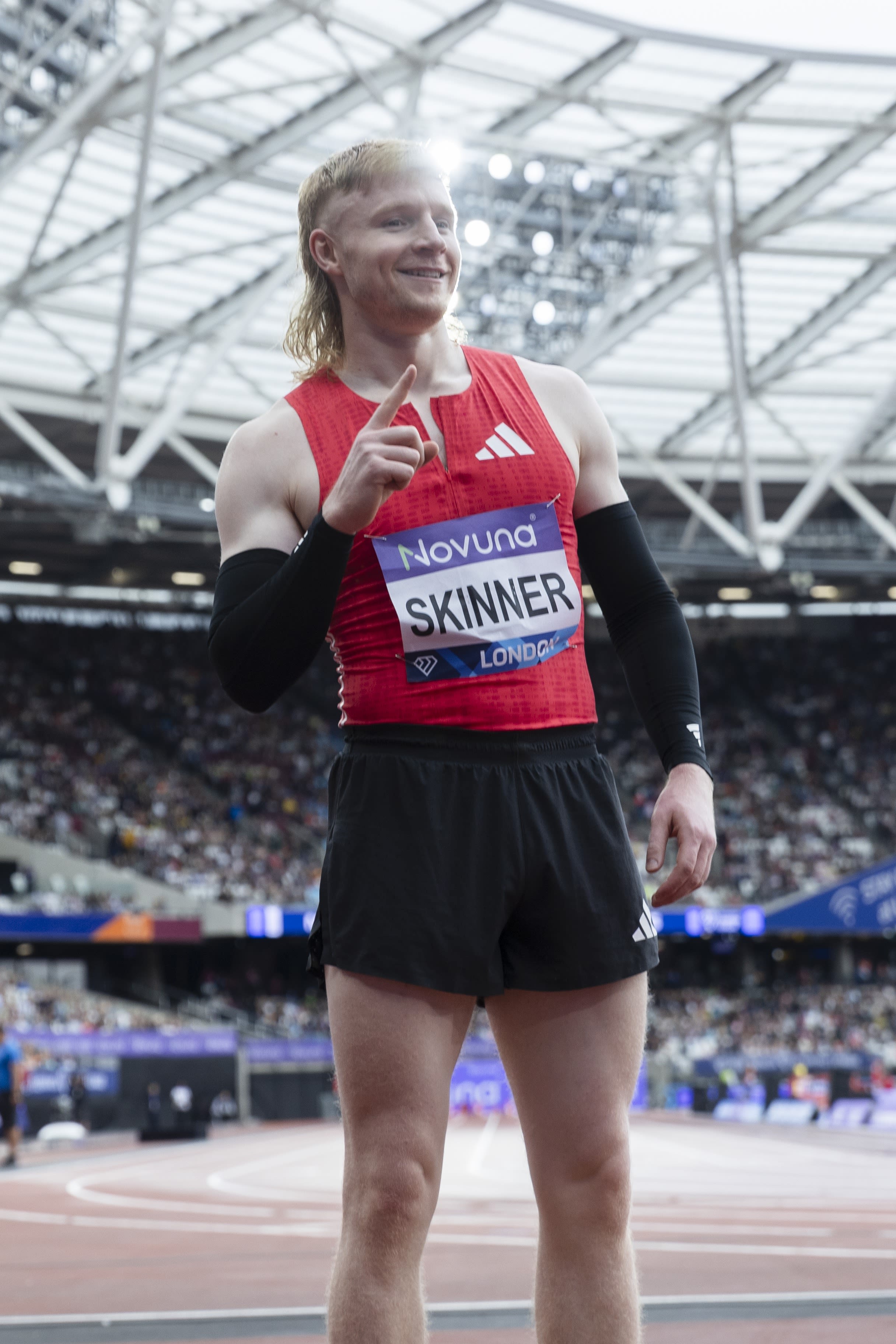 Zak Skinner stands in a red top and black shorts after competing at the London Stadium.