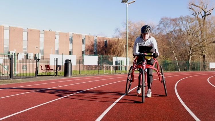 Paralympic athlete Tully Kearney stood on an athletics track using a running frame