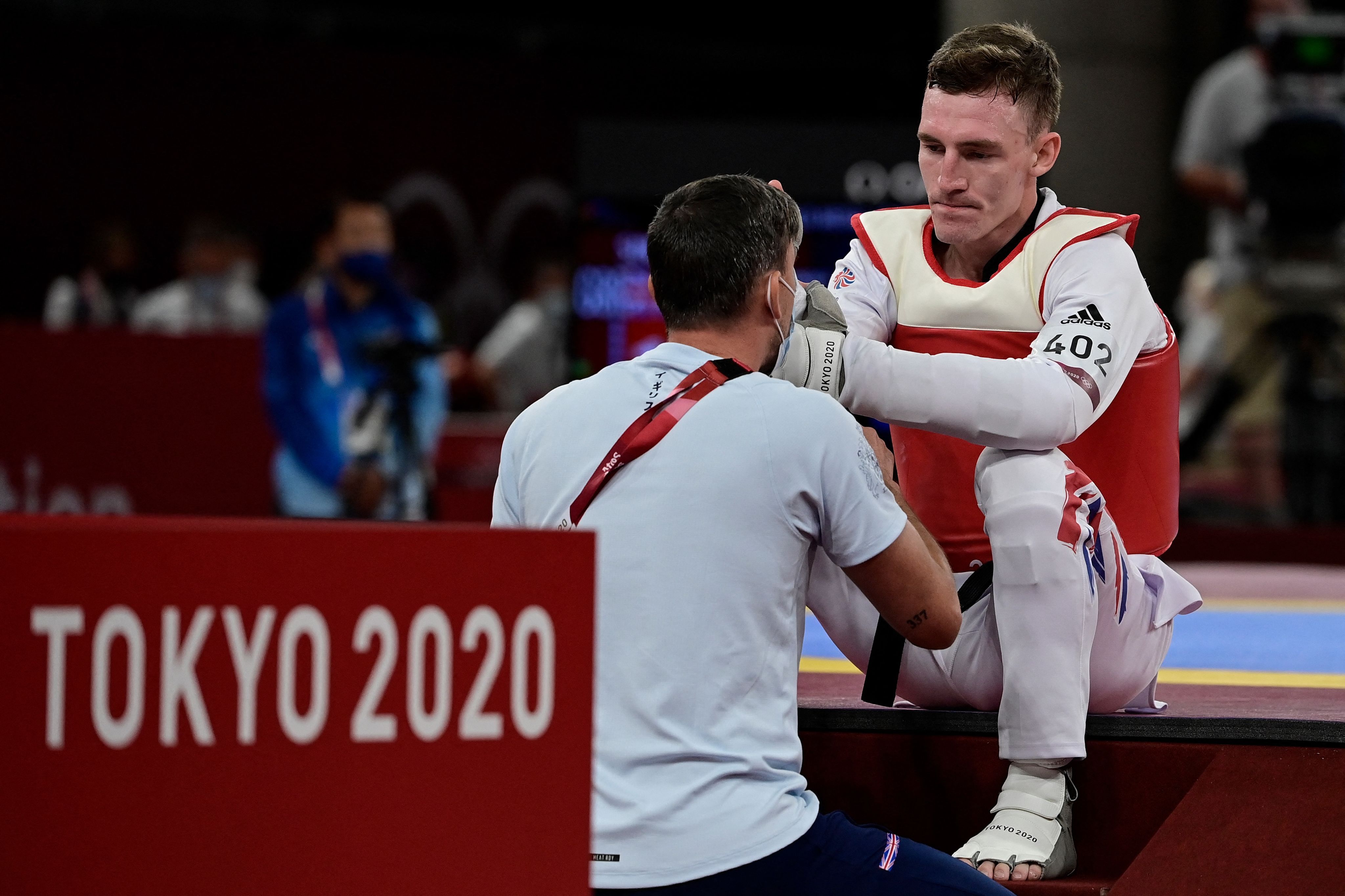 TeamGB taekwondo athlete sitting and being spoken to by a member of support staff