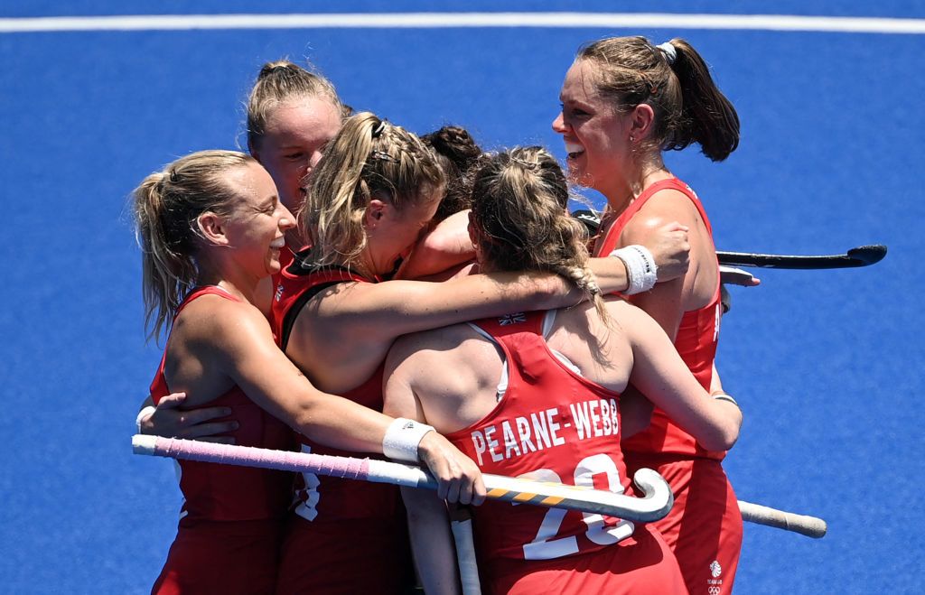 A group of six TeamGB hockey players hugging and celebrating together